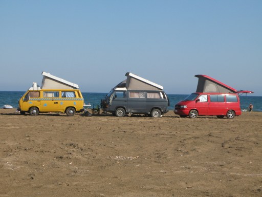 A couple of T3 & a T4 campervans on a beach camp site.